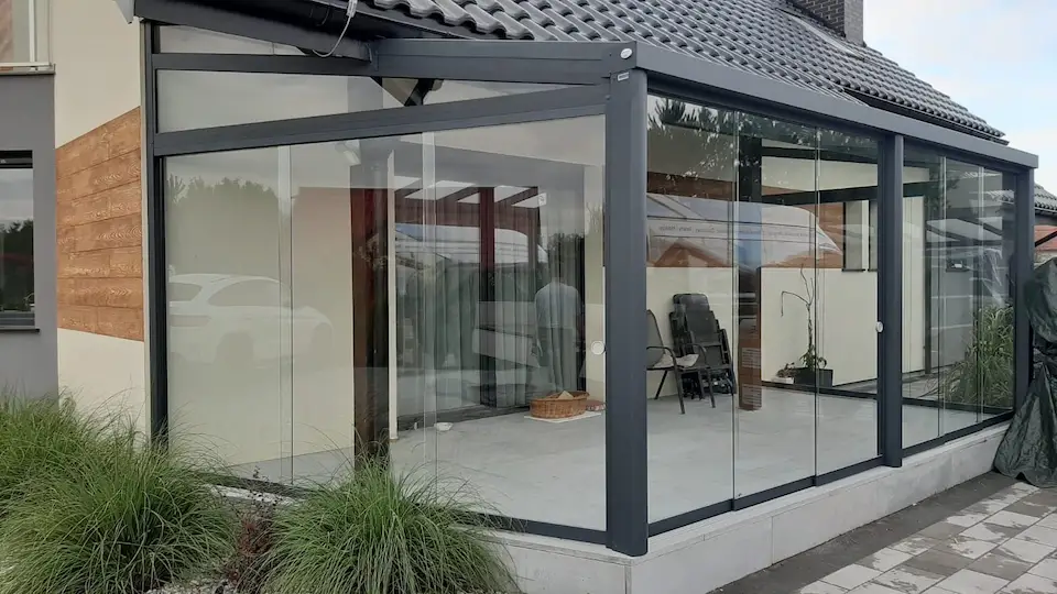 Modern enclosed patio featuring sliding glass walls with sleek grey framing.
