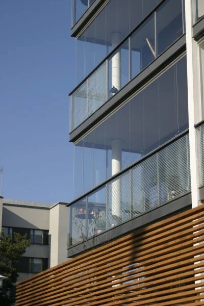 Contemporary apartment building with multiple balconies enclosed by glass and integrated railings for a sleek, minimalist design.