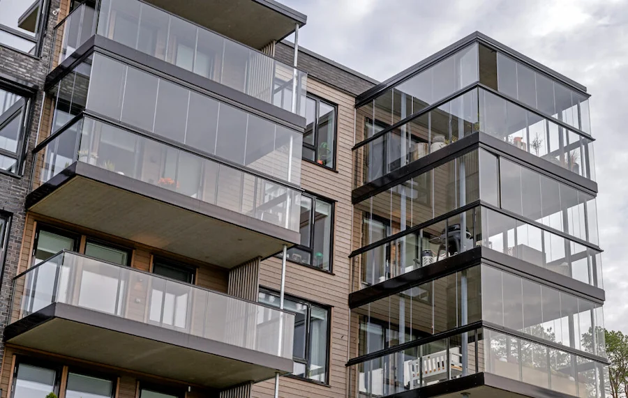 Modern apartment building featuring balconies enclosed with frameless folding glass walls for a sleek, contemporary finish.