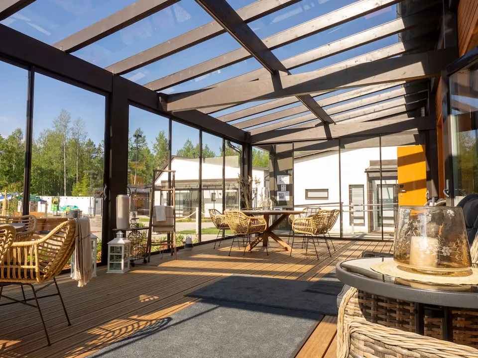 Contemporary sunroom featuring wood beam pergola and large sliding glass walls, supported by durable roof systems.