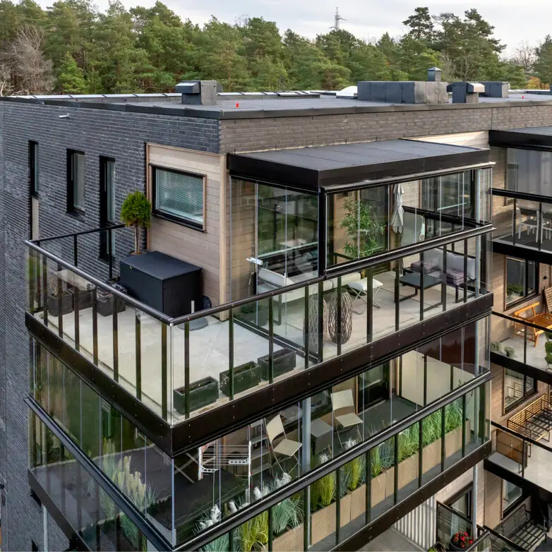 Contemporary apartment building with multiple glass-enclosed balconies, creating stylish outdoor living spaces with privacy.