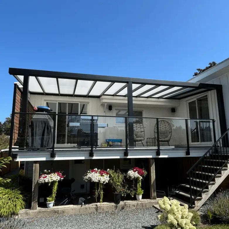 Elevated deck with integrated glass railing and modern glass roof canopy, decorated with hanging chairs and potted flowers.