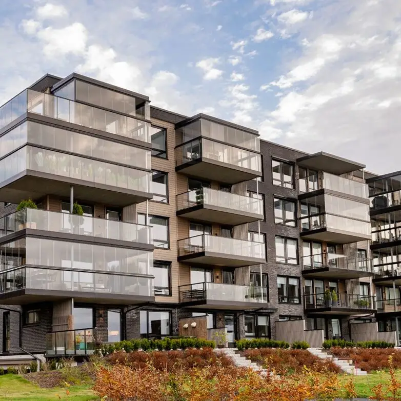 Contemporary apartment complex featuring multiple patio enclosures with sleek integrated glass railings.