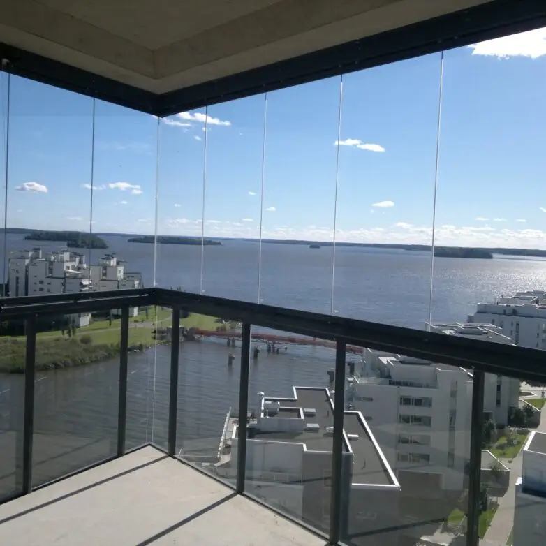 Corner balcony with integrated glass railings offering panoramic water views from a modern high-rise.