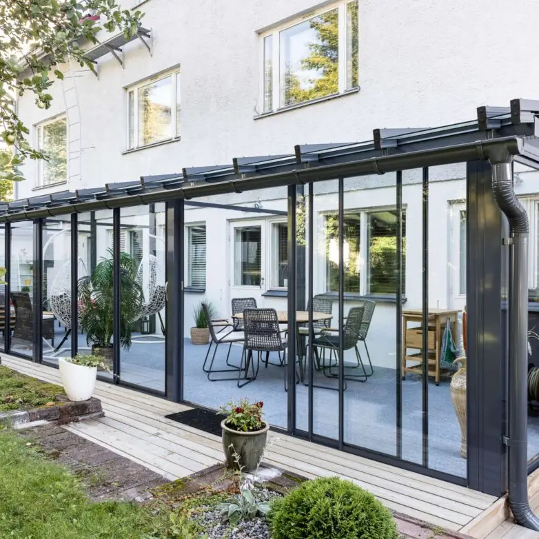 Residential sliding glass patio enclosure furnished with modern seating for year-round outdoor living.