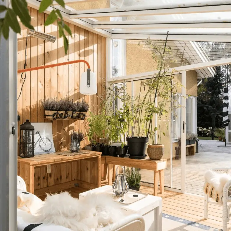 Bright sunroom with wooden interior walls, potted plants, and glass sliding doors opening to a patio.