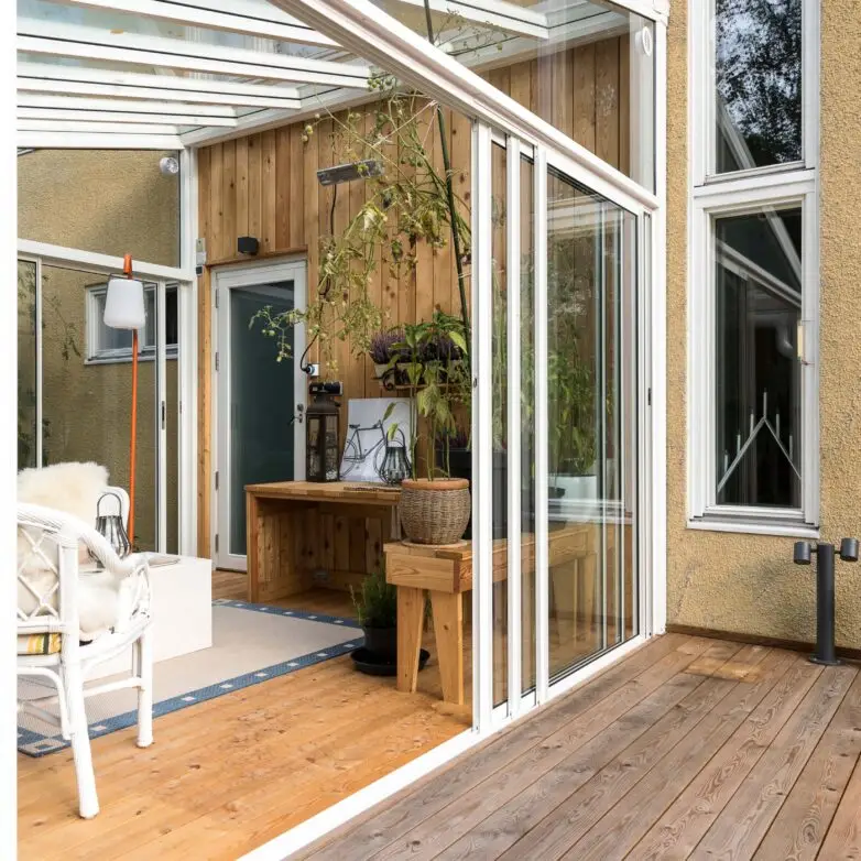 Bright sunroom with white-framed sliding glass walls and warm wood accents for a light-filled indoor garden space.
